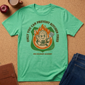 Green t-shirt with a graphic design on a cork surface with kitchen items.