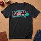 Black t-shirt lay flat on a corkboard surfce. says Proud to ba a Teacher
