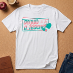 white  t-shirt lay flat on a corkboard surfce. says Proud to ba a Teacher