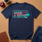 Navy t-shirt lay flat on a corkboard surfce. says Proud to ba a Teacher