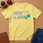 Cornsik {Light Yelloww t-shirt lay flat on a corkboard surfce. says Proud to ba a Teacher

