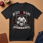 A black short-sleeve graphic t-shirt laid flat on a cork background, featuring a soccer-themed angry face design with the text 'NO GUTS 4:24 NO GLORY' and 'LEAVE IT ALL ON THE PITCH'.
