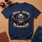A navy blue graphic t-shirt laid flat on a cork background, featuring a hockey player's helmet and crossed sticks with the text 'POCKS OVER EVERYTHING' and 'LEAVE IT ALL ON THE ICE'. Props around it include an apple, a coffee cup, a brown journal, and blue jeans.