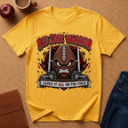 A yellow graphic t-shirt laid flat on a cork background, featuring a football-themed design with the text 'RED ZONE WARRIOR' and 'LEAVE IT ALL ON THE FIELD'. The shirt is styled with an apple, a coffee mug, a notebook, and blue jeans around it.