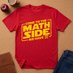 red graphic t-shirt laid flat on a brown cork background, featuring a yellow graphic that reads 'COME TO THE MATH SIDE WE HAVE π' styled with school and coffee props.