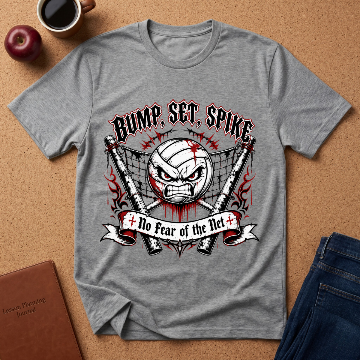A heather gray graphic t-shirt laid flat on a cork background, featuring a volleyball-themed design with the text 'BUMP, SET, SPIKE' and 'No Fear of the Net'. The shirt is styled with a coffee cup, an apple, a journal, and jeans.