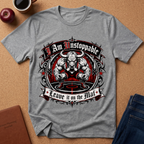 A heather gray short-sleeve t-shirt with a muscular bull graphic and the text 'I Am Unstoppable' and 'Leave it on the Mat', laid flat on a cork background with a coffee cup, apple, and jeans nearby.
