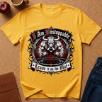 A yellow graphic t-shirt laid flat on a cork background with lifestyle props including an apple, a coffee mug, a notebook, and jeans. The shirt features a large central graphic of a muscular bull skull with the text 'I Am Unstoppable' above and 'Leave it on the Mat' below.