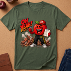 An olive green graphic t-shirt laid flat on a cork background, featuring a cartoon red apple character wearing a 'Gym Teacher' cap and sweatpants with the text 'OH YEAH!' and a clipboard.