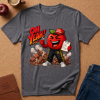 A dark gray graphic t-shirt laid flat on a cork background, featuring a cartoon red apple character wearing a 'GYM Teacher' cap and sweatpants with the text 'OH YEAH!' above it. Styled flat-lay props include an apple, coffee cup, notebook, and jeans.