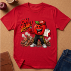 A red short-sleeve graphic T-shirt laid flat on a cork surface, featuring a cartoon red apple character wearing a cap that says 'GYM TEACHER' and holding a clipboard, with the text 'OH YEAH!' above. Surrounding props include an apple, a mug, a notebook, and blue jeans.