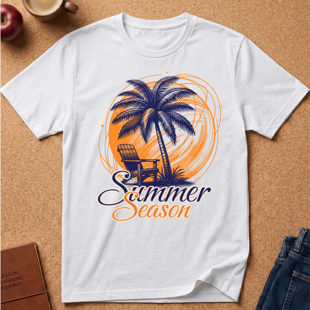 A white short-sleeve crewneck t-shirt laid flat on a cork background, featuring a graphic print of a palm tree, a chair, and the words 'Summer Season' in orange and navy blue.