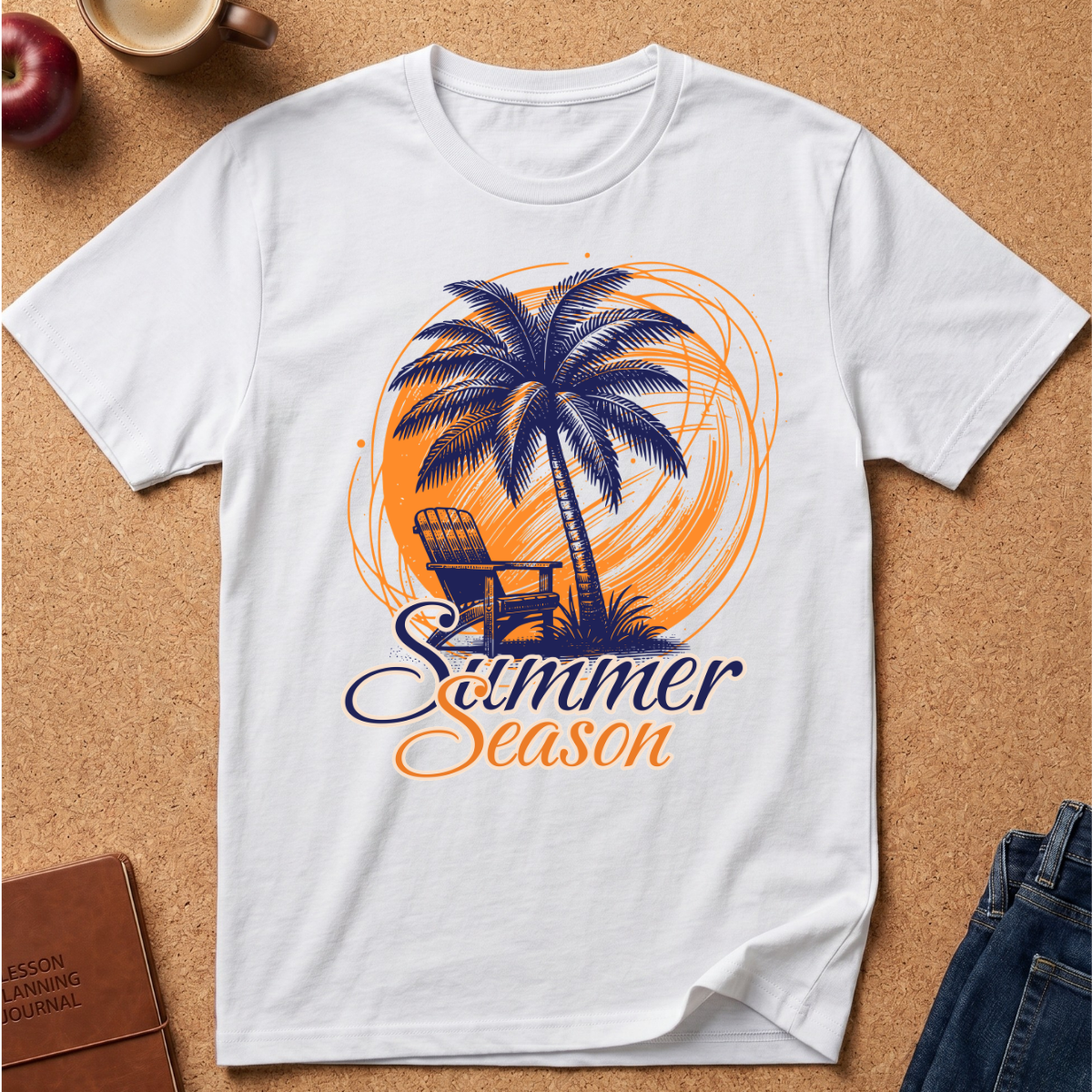 A white short-sleeve crewneck t-shirt laid flat on a cork background, featuring a graphic print of a palm tree, a chair, and the words 'Summer Season' in orange and navy blue.