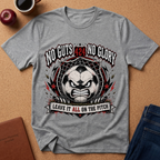 A heather gray graphic t-shirt laid flat on a cork board background, surrounded by lifestyle props including a coffee mug, an apple, a notebook, and folded blue jeans. The t-shirt features a large graphic of an angry soccer ball with the text 'NO GUTS 424 NO GLORY' and 'LEAVE IT ALL ON THE PITCH'.