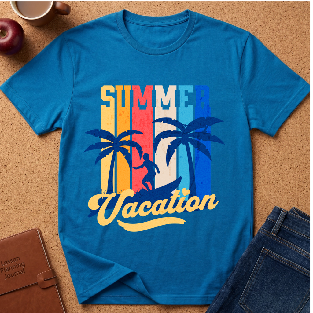 A bright blue short-sleeve t-shirt laid flat on a cork surface, featuring a retro-style 'Summer Vacation' graphic with palm trees and a sunset stripe design in yellow, orange, red, and blue. Styled flat-lay props include a brown leather journal, a dark apple, a coffee mug, and blue jeans.
