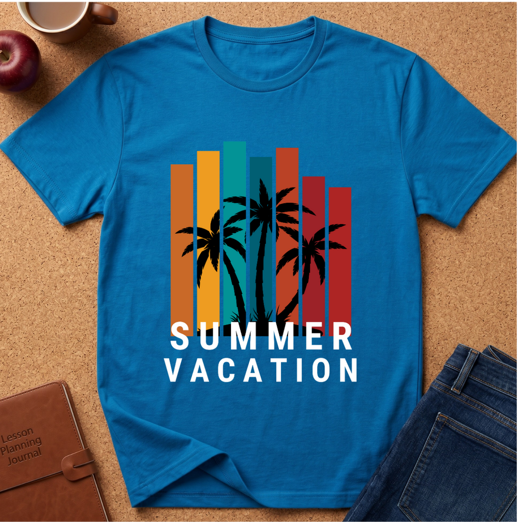 A bright blue short-sleeve t-shirt laid flat on a cork background, featuring a retro-style graphic with vertical multicolor bars, black palm tree silhouettes, and the words 'SUMMER VACATION' in white. Surrounding props include an apple, a coffee cup, a notebook, and folded jeans.