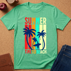 A mint green heather t-shirt laid flat on a cork background, featuring a retro vertical-stripe graphic with palm trees, a surfer silhouette, and the text 'SUMMER TIME TO BEACH' in multicolor letters. Styled flat-lay props include an apple, a notebook, and blue jeans.