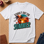 A white short-sleeve crewneck t-shirt laid flat on a cork board background, featuring a colorful graphic with the text 'SCHOOL'S OUT FOR SUMMER' and a tropical sunset scene with palm trees and birds.