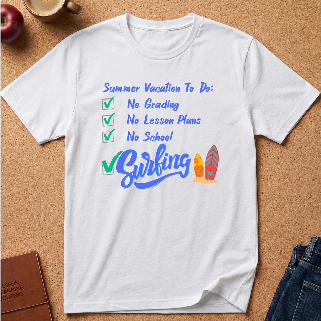 A white short-sleeve t-shirt laid flat on a cork background, featuring a colorful graphic that reads 'Summer Vacation To Do: No Grading, No Lesson Plans, No School' with a large checkmark and the word 'Biking' next to two surfboards.