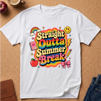 A white short-sleeve t-shirt laid flat on a cork background, featuring a colorful retro-style graphic that reads 'Straight Outta Summer Break' with rainbow lettering and school-themed doodles like a rainbow, apple, notebook, pencil, lightning bolt, and bow.