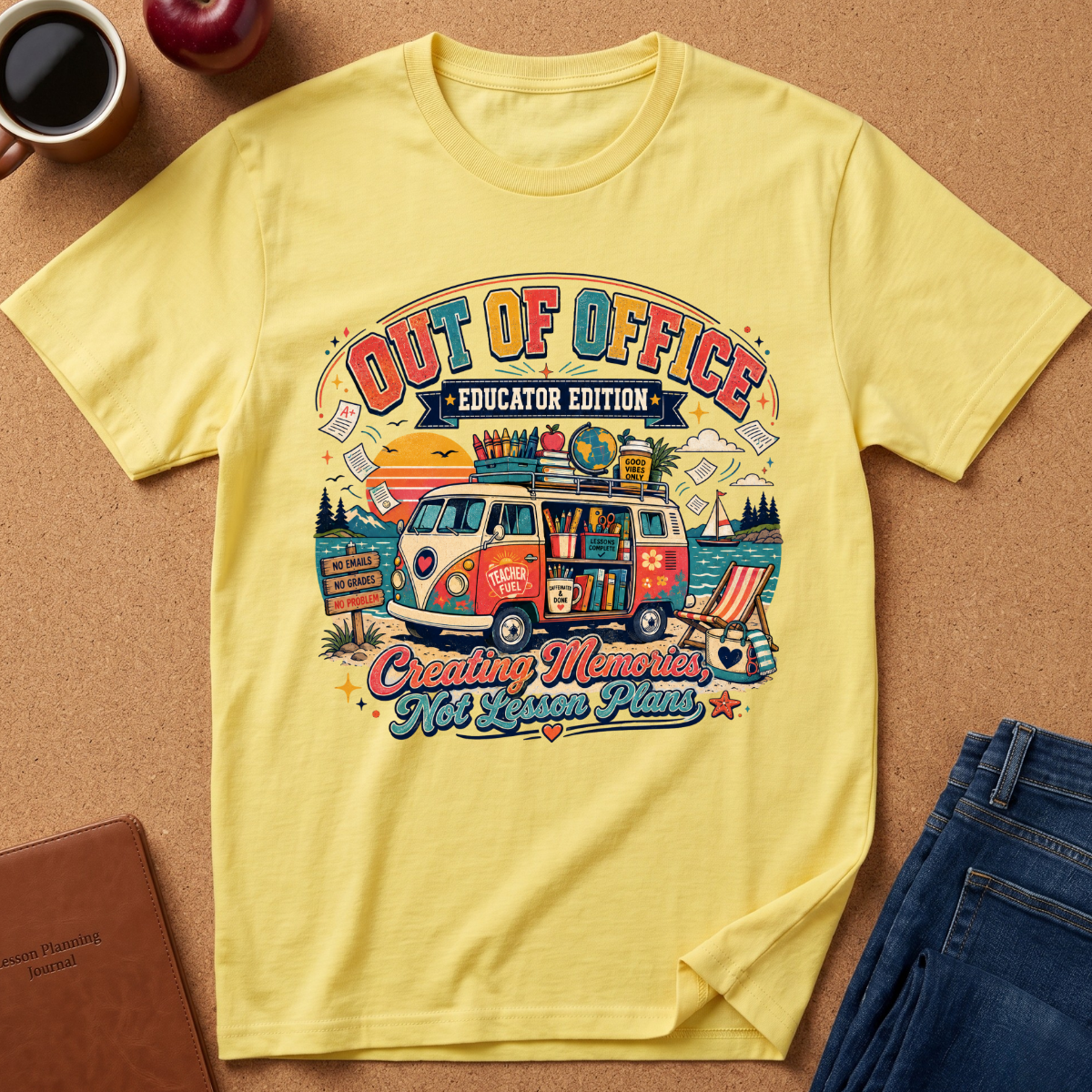 A yellow graphic t-shirt laid flat on a cork background, surrounded by lifestyle props including a coffee mug, an apple, a notebook, and a pair of blue jeans. The t-shirt features a colorful retro-style graphic of a VW bus with the text 'OUT OF OFFICE EDUCATOR EDITION' and 'Creating Memories Not Lesson Plans'.