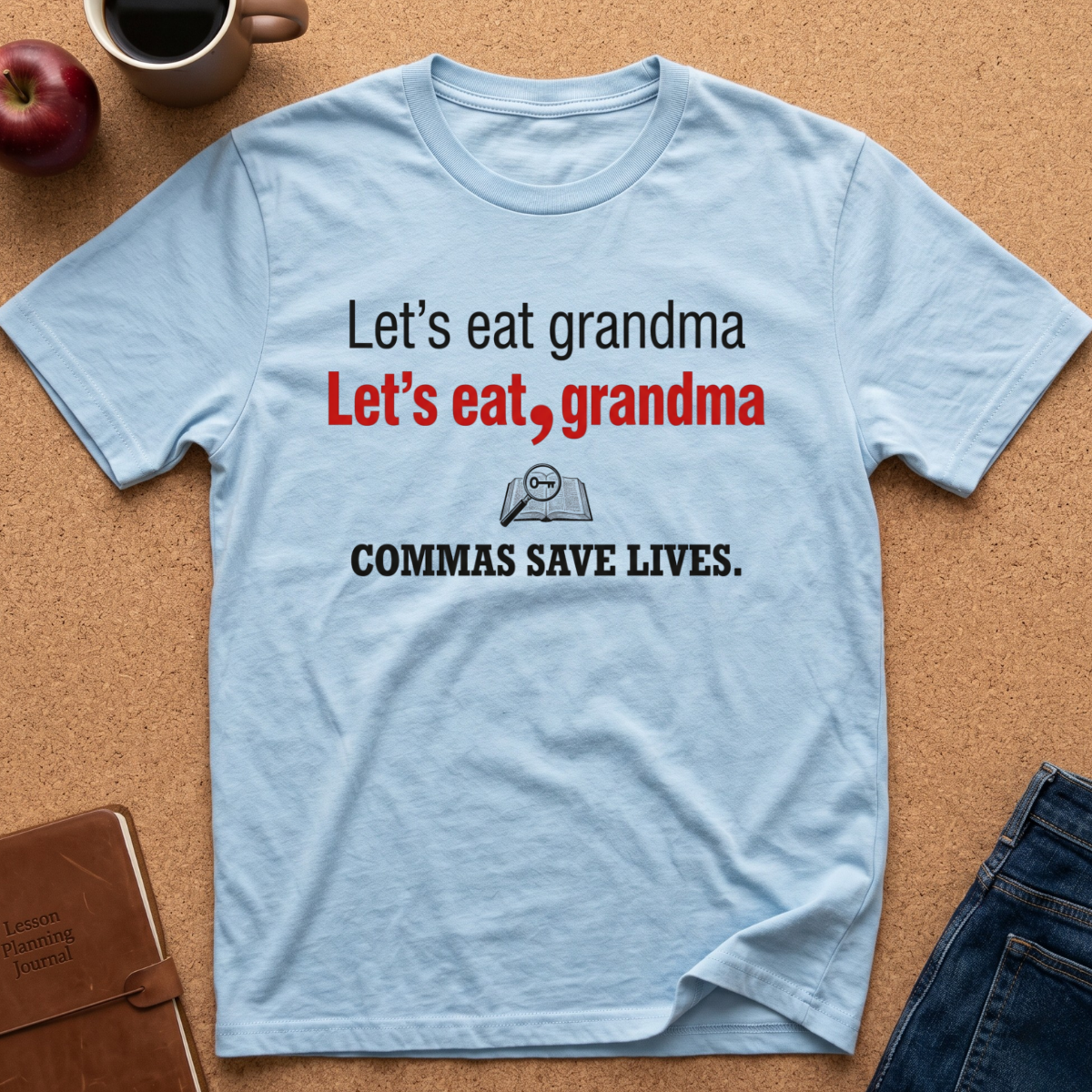 A light blue graphic t-shirt laid flat on a cork background, featuring the text 'Let's eat grandma' in black and red, with a small magnifying glass icon and 'COMMAS SAVE LIVES.' in black below.