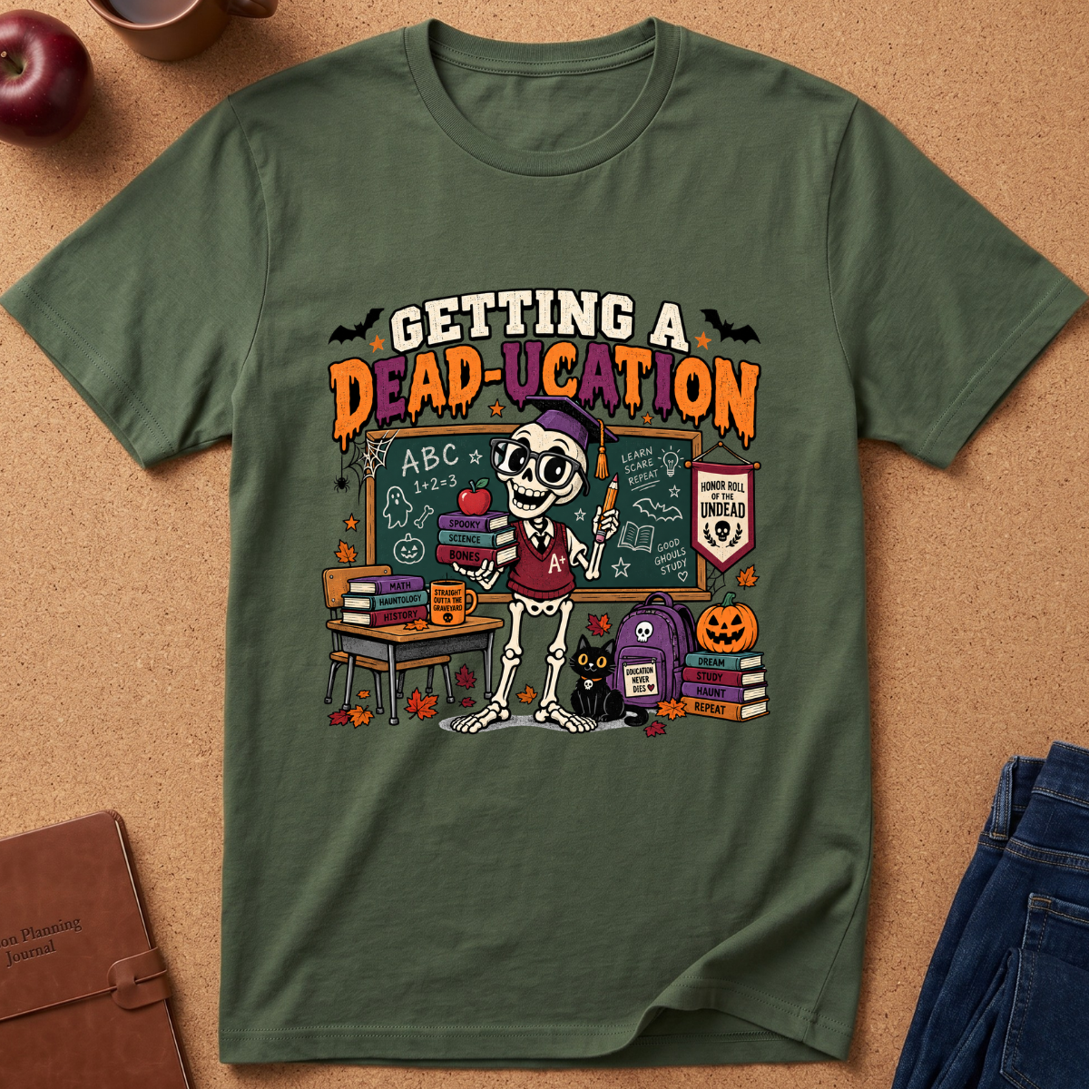 An olive green graphic t-shirt laid flat on a cork background, featuring a cartoon skeleton teacher in a classroom with the text 'GETTING A DEAD-UCATION'.