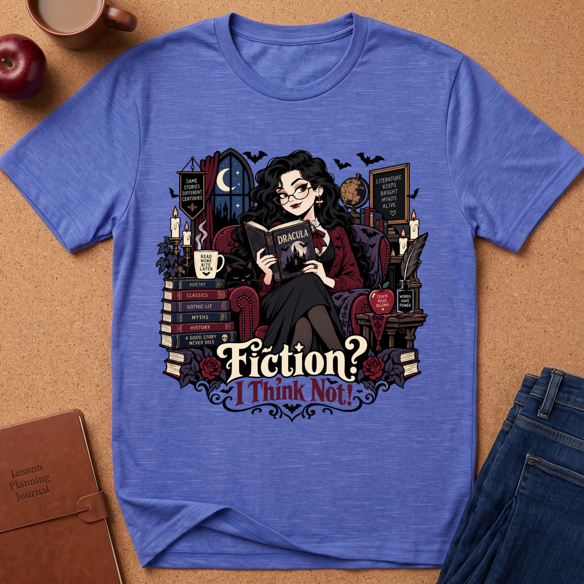 A heathered blue crewneck t-shirt with a detailed graphic of a witch reading a book, surrounded by books, candles, and a cauldron, with the text 'Fiction? I Think Not!'. The shirt is displayed in a flat-lay arrangement on a cork background with an apple, coffee mug, notebook, and jeans.