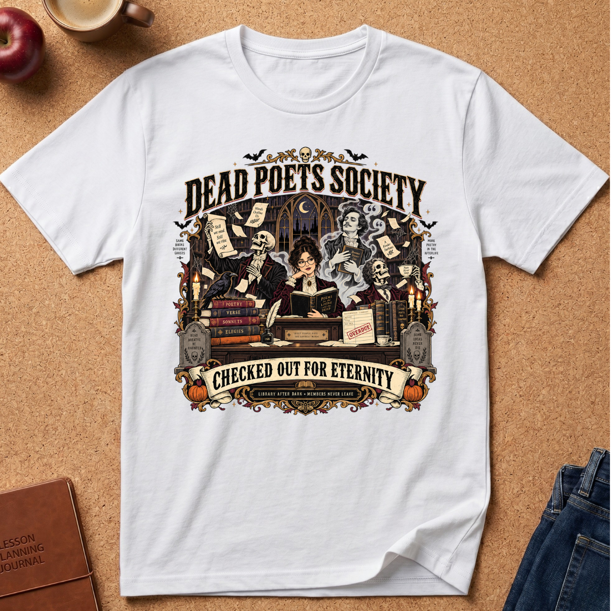 A white short-sleeve graphic T-shirt laid flat on a cork board background, featuring a detailed Halloween-themed illustration with skeletons, books, candles, and the text 'Dead Poets Society' and 'Checked Out for Eternity.' Styled props including an apple, a mug, a journal, and jeans are partially visible around the shirt.