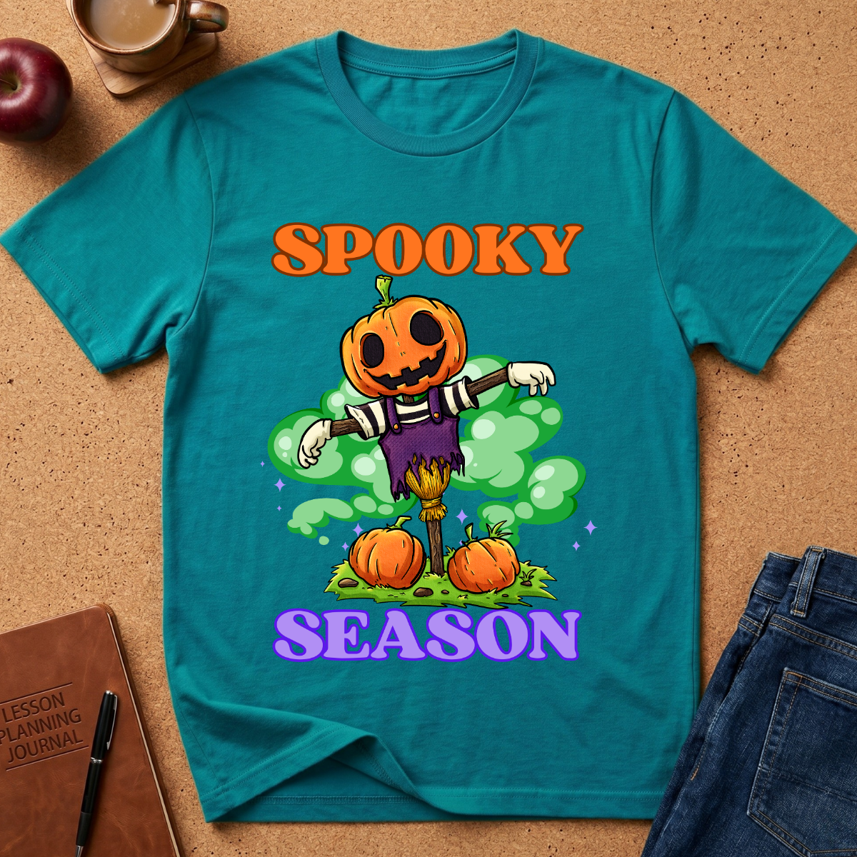 tropicl blue Spooky Season Pumpkin T-Shirt pairs a grinning jack-o’-lantern rising through green mist with scattered pumpkins and bold retro “SPOOKY SEASON” lettering. 