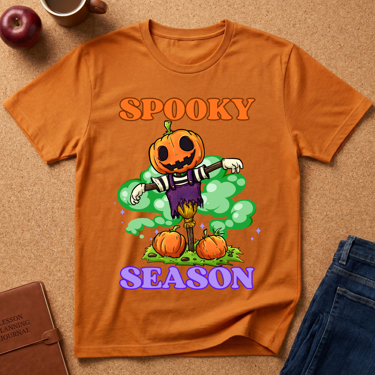 Orange Spooky Season Pumpkin T-Shirt pairs a grinning jack-o’-lantern rising through green mist with scattered pumpkins and bold retro “SPOOKY SEASON” lettering. 