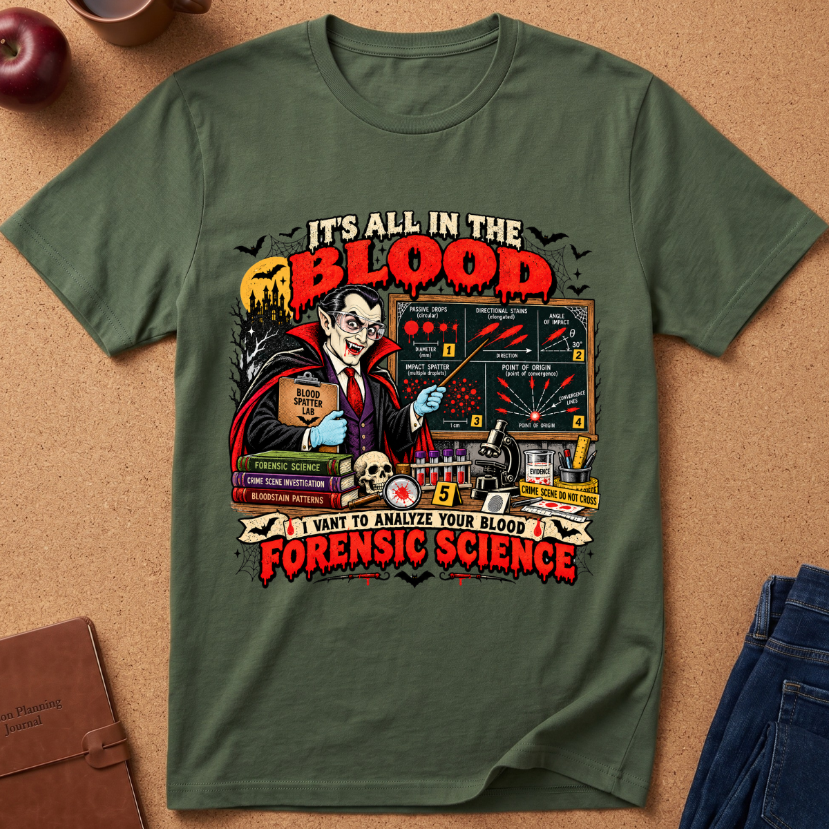 An olive green graphic t-shirt laid flat on a brown cork background, featuring a detailed horror-themed design with Dr.acula, blood tests, a skull, and the text 'IT'S ALL IN THE BLOOD' and 'I WANT TO ANALYZE YOUR BLOOD FORENSIC SCIENCE'.