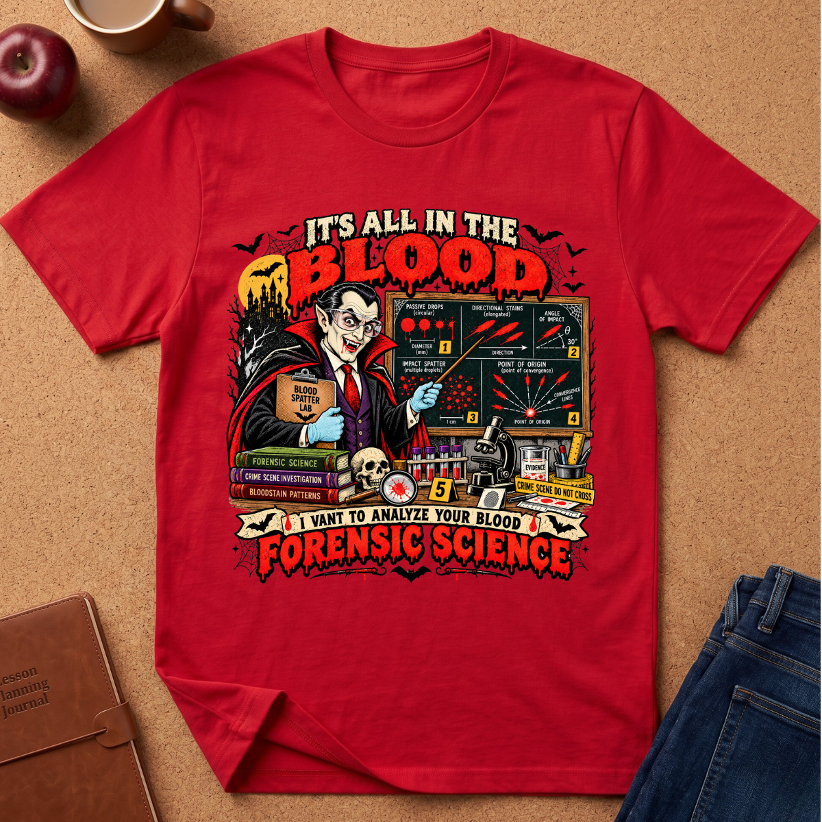 A red short-sleeve graphic T-shirt laid flat on a cork surface, surrounded by styled props including an apple, a coffee cup, a journal, and blue jeans. The shirt features a large horror-themed forensic science print with the text 'IT'S ALL IN THE BLOOD' and 'I WANT TO ANALYZE YOUR BLOOD FORENSIC SCIENCE' plus illustrated elements like a vampire, blood test results, a skull, and books.
