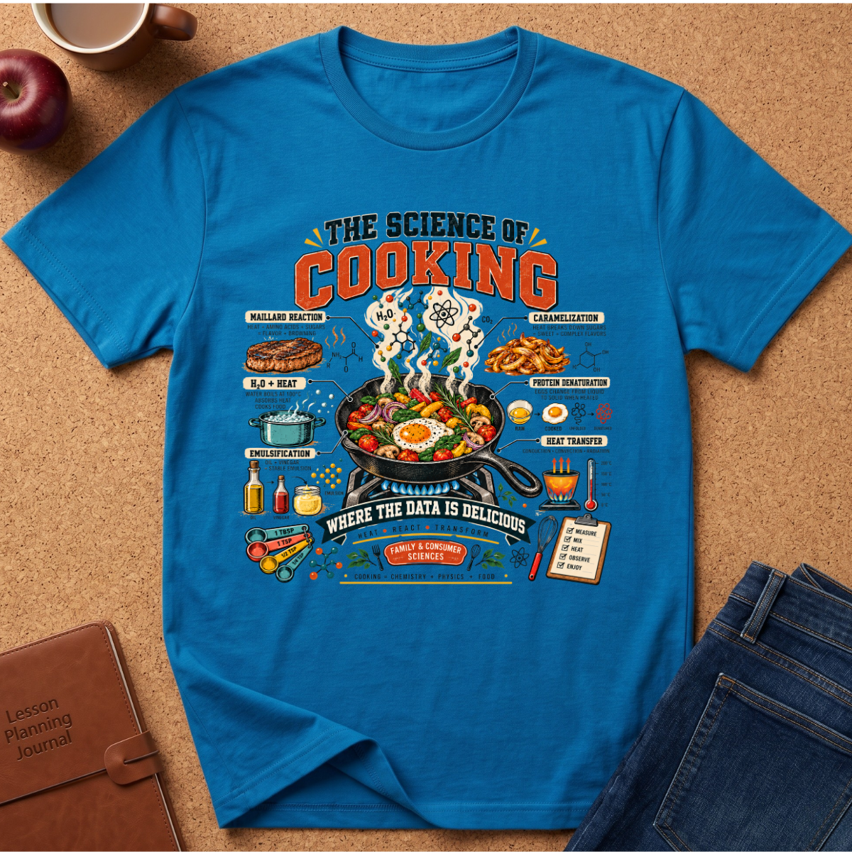 A bright blue graphic t-shirt laid flat on a cork board background, surrounded by lifestyle props including an apple, a coffee cup, a leather journal, and jeans. The t-shirt features a detailed, colorful cooking-themed illustration with text like 'THE SCIENCE OF COOKING' and 'WHERE THE DATA IS DELICIOUS'.