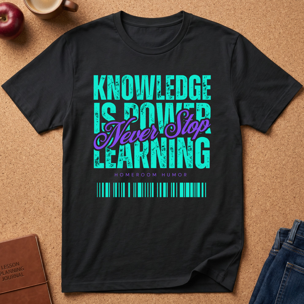 A black graphic t-shirt laid flat on a cork background, featuring the text 'KNOWLEDGE IS POWER LEARNING' in distressed teal, with 'Never Stop' in purple script. The shirt is styled with a lesson planning journal, an apple, a mug, and jeans.