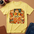A pale yellow graphic T-shirt laid flat on a tan surface, surrounded by styled props including a coffee mug, apple, notebook, and jeans. The shirt features a large autumn-themed cartoon print with the phrase 'Everyone has a Roll' in fall colors and small character illustrations.