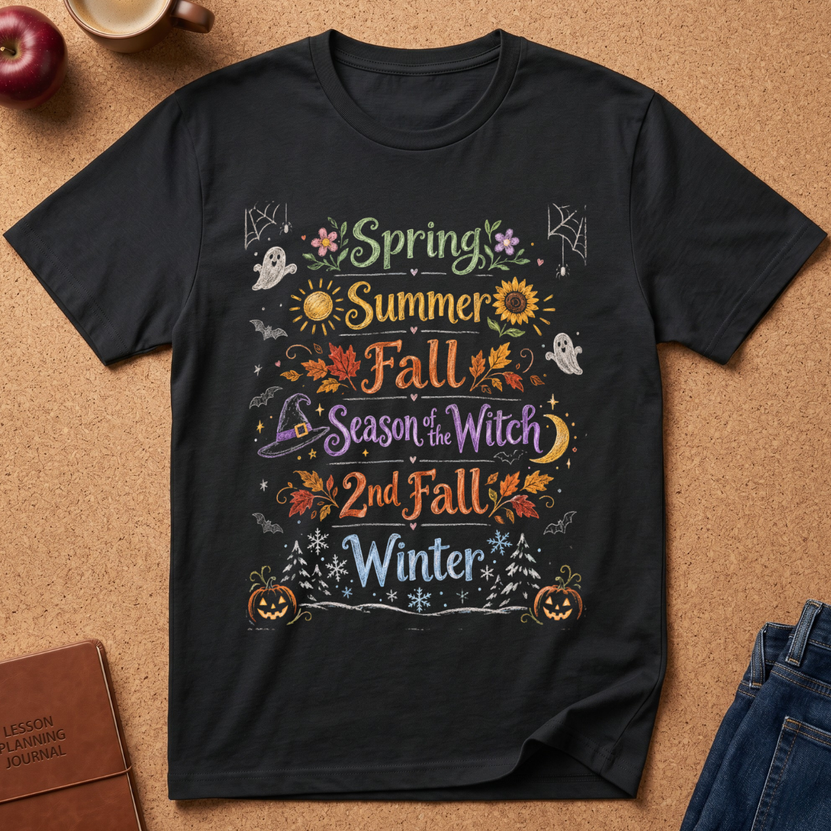 A black graphic t-shirt laid flat on a cork background, featuring a colorful seasonal design that reads 'Spring Summer Fall Season of Witch 2nd Fall Winter' with Halloween-themed illustrations including pumpkins, ghosts, sunflowers, and leaves.