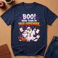 Navy blue Graphic short sleeves T-Shirt with a cute ghost looking upset with a red pen and a pile of gra Ed homework, saying BOO, Now Turn In Your Homework.