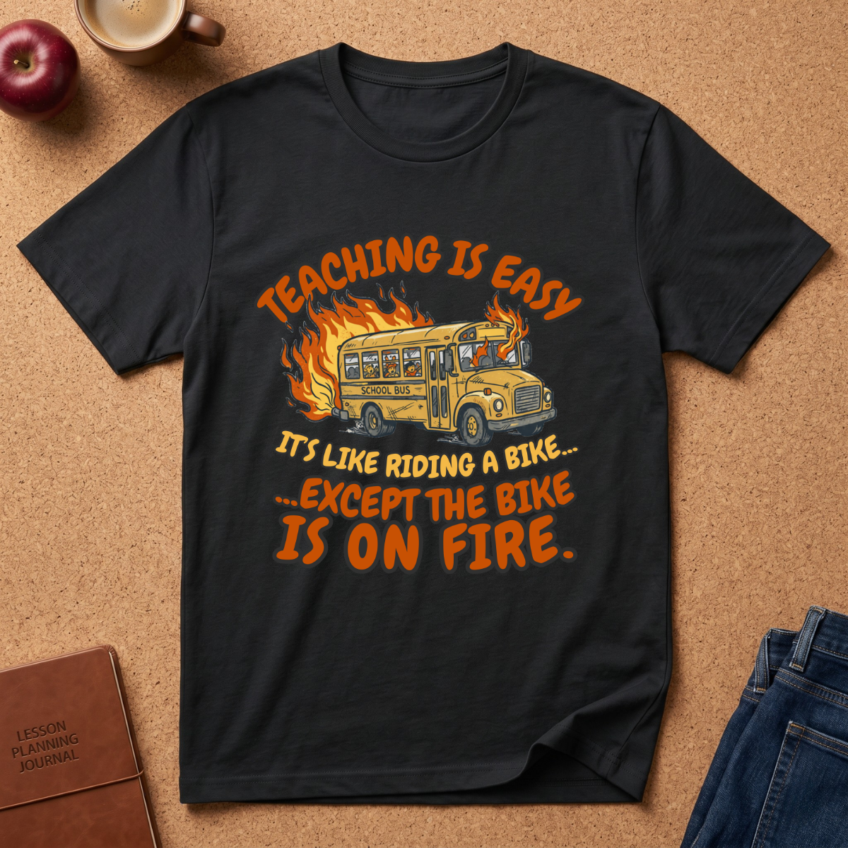 Black t-shirt with a humorous design of a school bus on fire, text 'Teaching is easy. It's like riding a bike.  except the Bike is on fire.