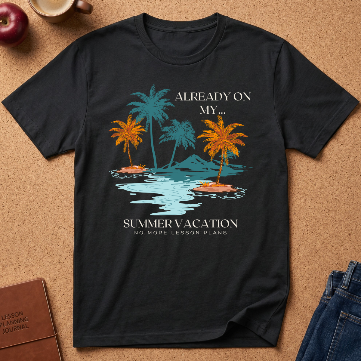 A black graphic t-shirt laid flat on a cork background, featuring a tropical island design with palm trees, water, and the text 'ALREADY ON MY SUMMER VACATION, NO MORE LESSON PLANS.