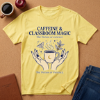 Yellow t-shirt with 'Caffeine & Classroom Magic' design on a brown surface with coffee and an apple.