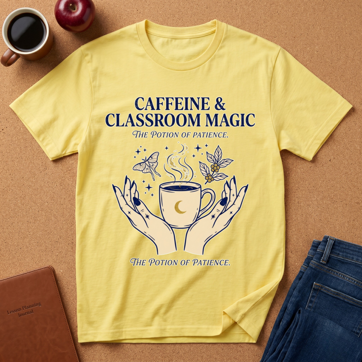 Yellow t-shirt with 'Caffeine & Classroom Magic' design on a brown surface with coffee and an apple.
