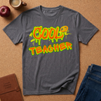 Gray t-shirt with 'Cool Teacher' text on a brown surface with a coffee cup, apple, and notebook.