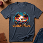 Heather Navy graphic t-shirt laid flat on a cork background, featuring a retro sunset car design with palm trees and the text 'TAKE ME WHERE SUMMER NEVER ENDS Vacation 