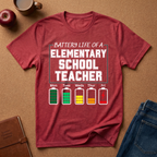Red t-shirt with 'Elementary School Teacher' graphic on a brown surface with school supplies.