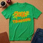 Green t-shirt with 'Cool Teacher' text on a brown surface with a coffee cup and apple.