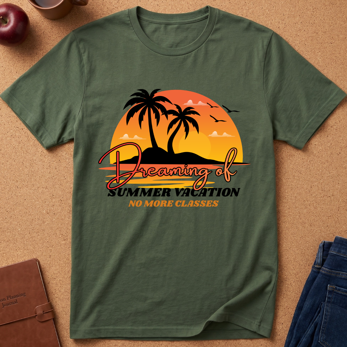 An olive green short-sleeve t-shirt laid flat on a cork background, featuring a retro sunset graphic with palm trees, birds, and the text 'Dreaming of Summer Vacation NO MORE CLASSES'.