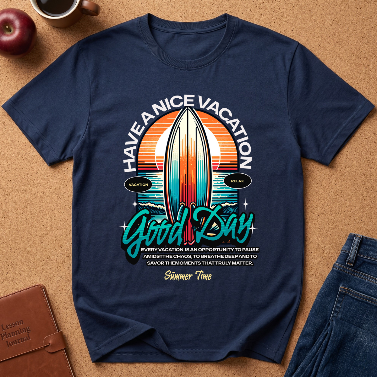 A navy blue graphic t-shirt laid flat on a brown cork background, surrounded by lifestyle props including a coffee cup, an apple, a notebook, and jeans. The t-shirt features a retro surfboard design with the text 'HAVE A NICE VACATION Good Day' and a humorous vacation-themed quote.