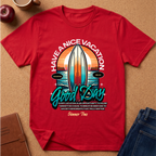 A red short-sleeve graphic T-shirt laid flat on a cork-like surface, with a large surfboard and sunset print reading “HAVE A NICE VACATION Good Day Summer Time.” Jeans, an apple, a mug, and a notebook are partially visible around it as styling props.