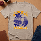 A beige graphic t-shirt laid flat on a cork background, featuring a blue and yellow retro sunset beach scene with the words 'SUMMER Vacation' and 'SUN-SALT SAND'.